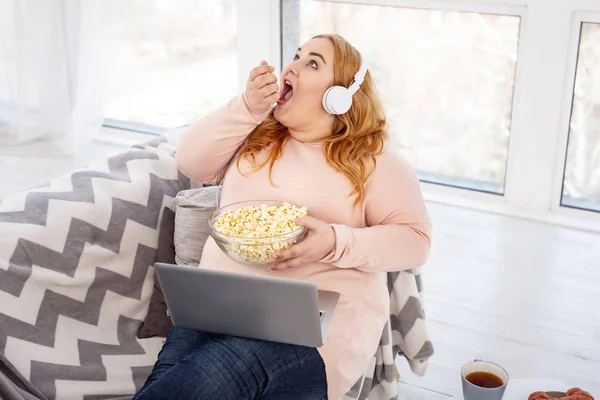 Wachsame, dicke Frau isst viel Popcorn — Stockfoto
