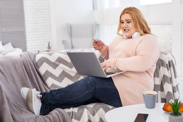 Mujer con sobrepeso disgustada sosteniendo un crédito — Foto de Stock