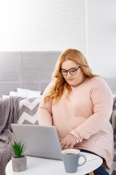 Koncentrerad stout kvinna som arbetar på sin laptop — Stockfoto