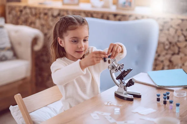 Chica alegre agradable usando el microscopio — Foto de Stock