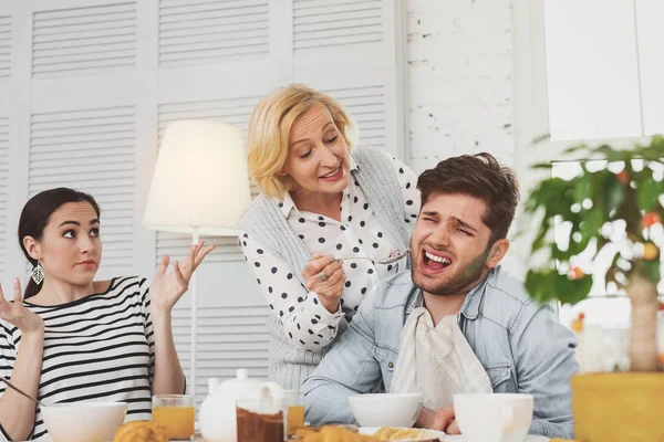 Mulher idosa agradável tentando alimentar seu filho — Fotografia de Stock