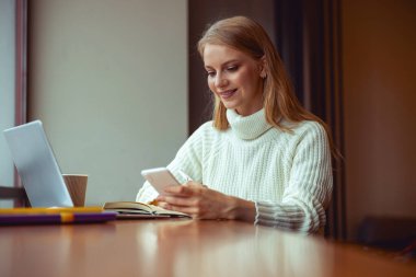 Kafede akıllı telefon kullanan bir kız.