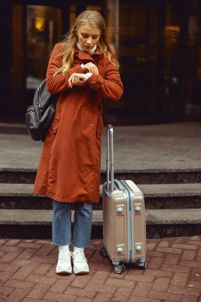 Fokussierte Frau, die die Zeit auf ihrer Uhr kontrolliert — Stockfoto