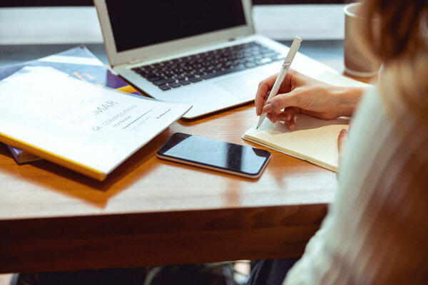 Кавказская студентка делает грамматические упражнения в помещении
