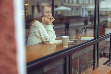 Kadın açık bir dizüstü bilgisayarın önünde oturuyor.