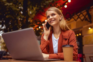 Gülümseyen serbest çalışan kadın telefonda konuşuyor.