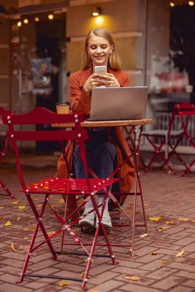 Mooi blank meisje met een mobiele telefoon buiten — Stockfoto