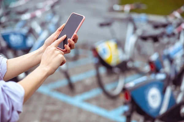 Vrouw met een mobiele telefoon huren van een sociale fiets — Stockfoto