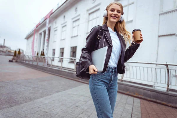 Sonriendo mujer caucásica en auriculares de pie al aire libre — Foto de Stock