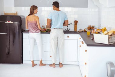 Genç ve mutlu uluslararası çift lezzetli yemekler pişiriyor.