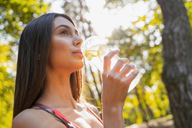 Kadın sabah egzersizlerinden sonra dışarıda içiyor.