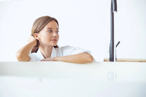 Мечтательная молодая женщина проводит время в ванной комнате — стоковое фото
