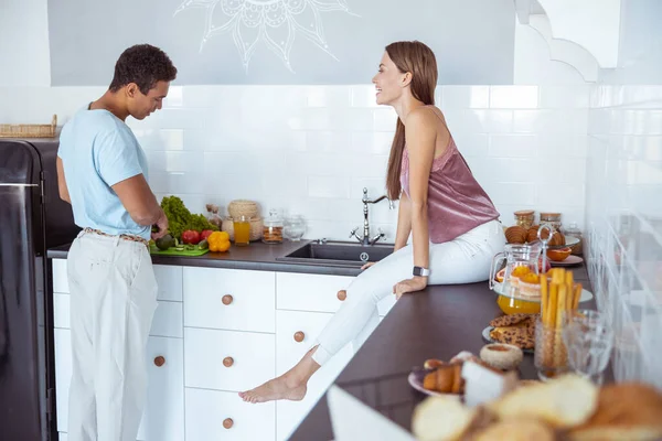 Verspieltes langhaariges Mädchen, das auf dem Tisch sitzt — Stockfoto