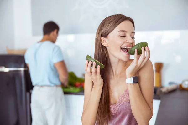 Close up of pretty girl is biting avocado — Stock Photo, Image