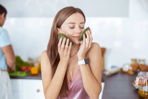 Charming young woman smelling aroma of fresh avocado — Stock fotografie