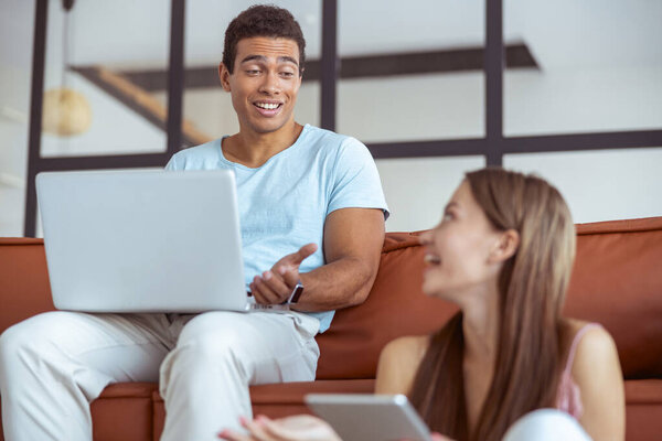 Cheerful young international couple having pleasant conversation