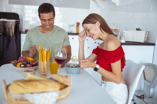 Gioiosa giovane donna che ride mentre mangia — Foto Stock