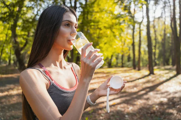 Bella donna che beve acqua dopo l'allenamento all'esterno — Foto Stock