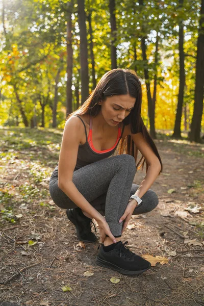 Mujer bonita lastimándose la pierna durante el jogging — Foto de Stock