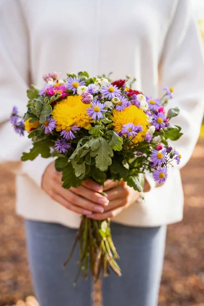Donna che tiene fiori autunnali durante la sua passeggiata — Foto Stock