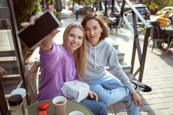 Chica de pelo largo alegre demostrando su nuevo teléfono inteligente — Foto de Stock