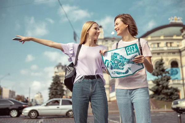 Positivas meninas encantadas andando junto com o mapa — Fotografia de Stock