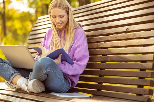 Chica encantada positiva haciendo tarea en casa en el parque — Foto de Stock