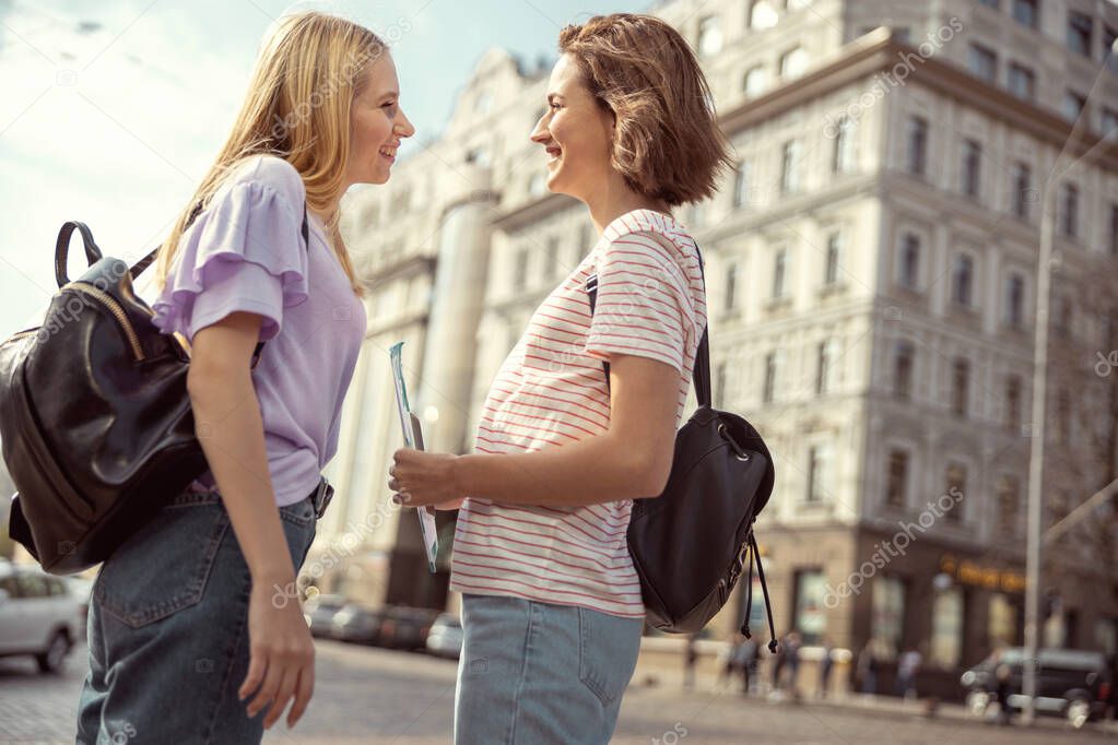 Positive delighted young women having friendly conversation