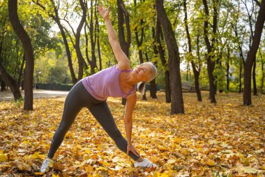 Dışarıda yoga yapan hoş, formda bir bayan.