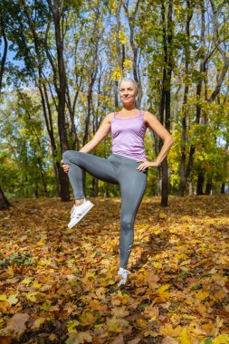 Gülümseyen atletik kadın bacak esnetiyor.