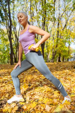 Atletik kadın ağırlıkları hamleler için kullanıyor.