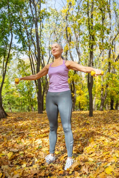 Senhora fazendo um exercício de braço usando halteres — Fotografia de Stock