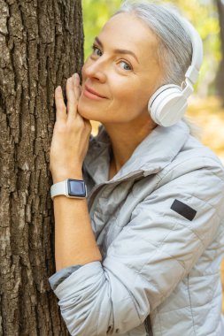 Mutlu, gevşemiş kadın ağaca yaslanıyor.
