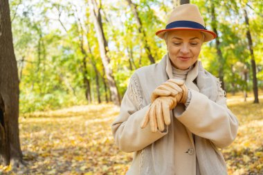 Gülümseyen beyaz kadın bileğine bakıyor.