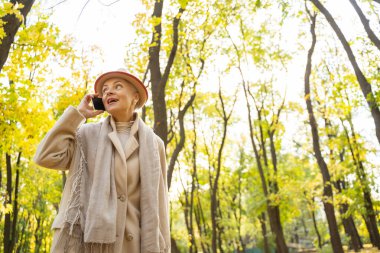 Cep telefonlu mutlu bir kadın başka tarafa bakıyor.