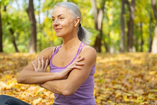 Fokussierte Frau mit verschränkten Armen, die draußen sitzt — Stockfoto