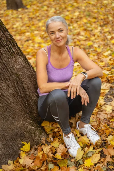 Parkta yerde oturan sportif bir bayan. — Stok fotoğraf