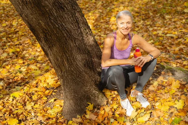 Sonriendo bonita hembra sosteniendo una botella deportiva — Foto de Stock