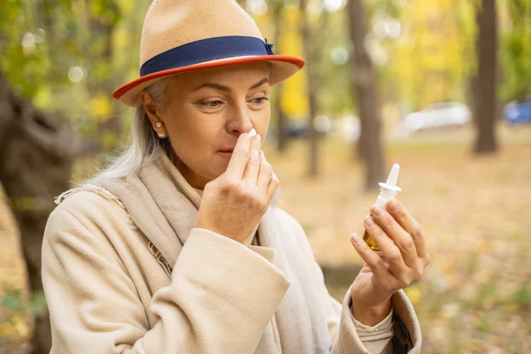 Serious female using her nasal drops outdoors — Stock Photo, Image
