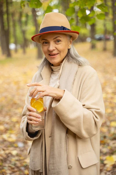 Kobieta trzymająca w rękach napój cytrusowy — Zdjęcie stockowe