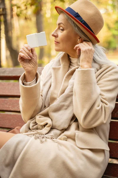 Женщина с карманным зеркалом сидит на улице — стоковое фото