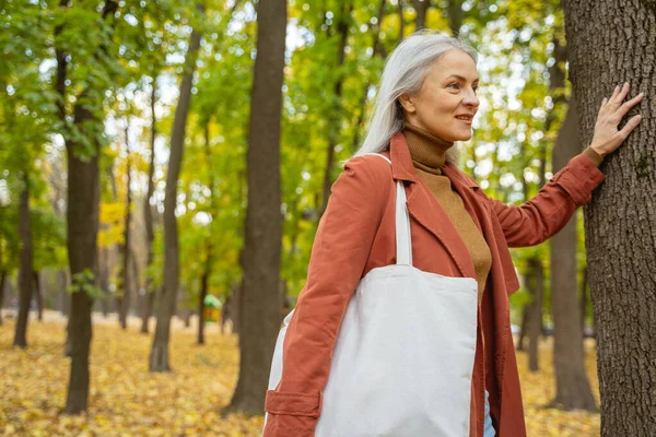 Pretty female standing near a tree trunk — Stock Photo, Image