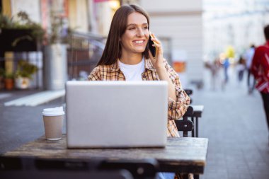 Neşeli bayan kafenin dışında arkadaşını bekliyor.