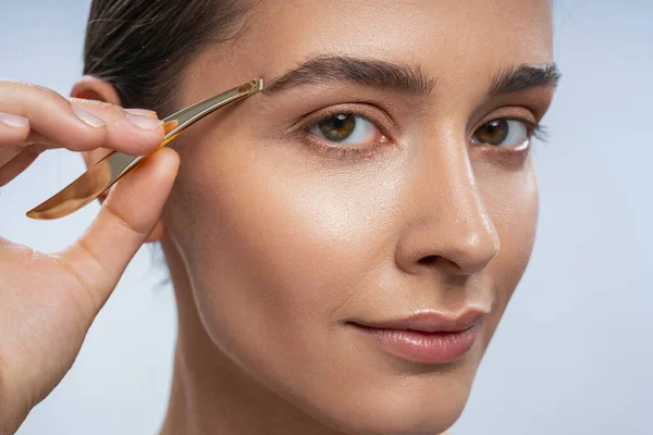 Close up of attentive woman that correcting her eyebrows — Stock Photo, Image