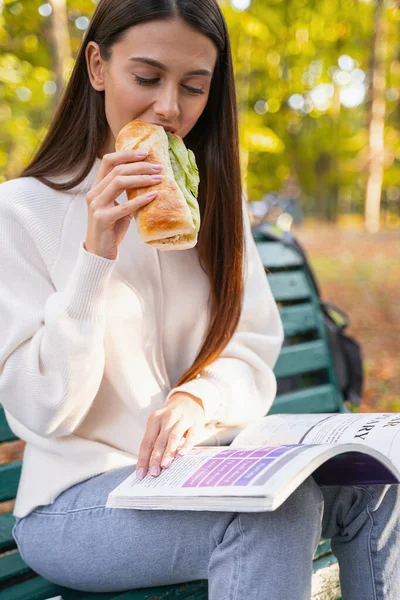Приваблива дівчина їсть смачний бутерброд у парку — стокове фото