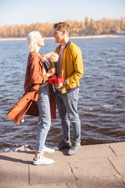 Bonito homem dando a sua namorada flor monte — Fotografia de Stock