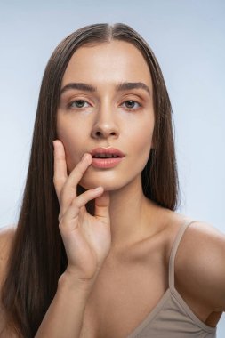 Çekici uzun saçlı esmer doğrudan kameraya bakıyor.