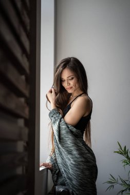 Pencerenin yanındaki omuzlarında ekoseli kadın.