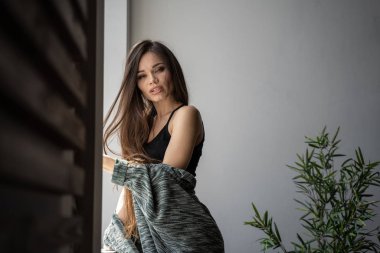 Uzun saçlı kız pencerenin önünde, gün ışığında.