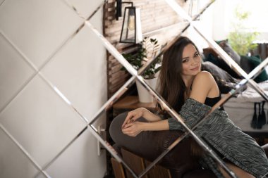 Aynanın önünde deri koltukta oturan kadın.